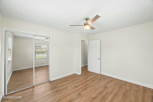 unfurnished bedroom with baseboards, wood finished floors, and a closet