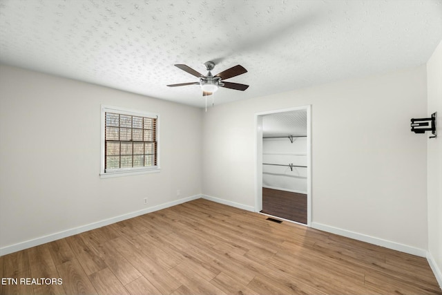 unfurnished bedroom featuring baseboards, a textured ceiling, visible vents, light wood-style flooring, and a closet