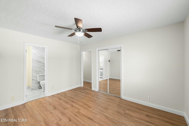 unfurnished bedroom featuring baseboards, a closet, wood finished floors, and a textured ceiling