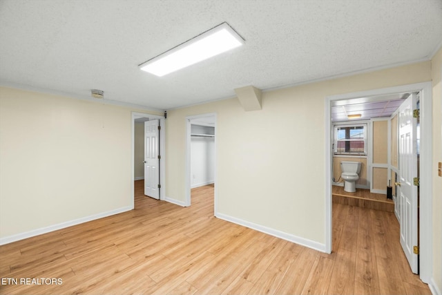unfurnished room with baseboards, a textured ceiling, and light wood-style floors