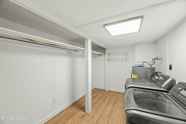 laundry area with water heater, independent washer and dryer, light wood-type flooring, and laundry area