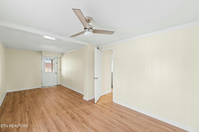empty room featuring a textured ceiling, light wood-style floors, baseboards, and a ceiling fan