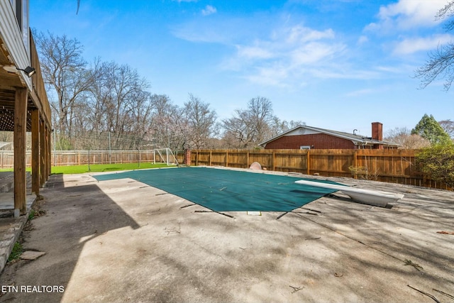 view of swimming pool with a patio, a fenced in pool, a fenced backyard, and a diving board