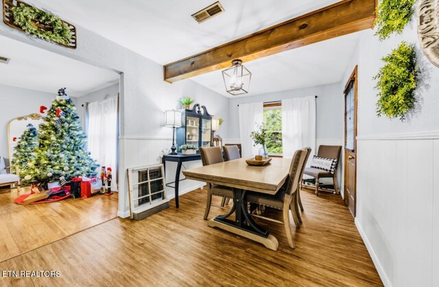 dining room with visible vents, wood finished floors, beamed ceiling, and wainscoting
