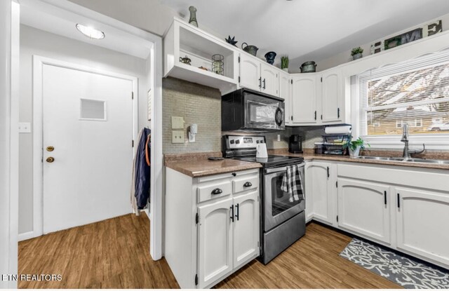 kitchen featuring electric range, a sink, black microwave, and light wood-type flooring