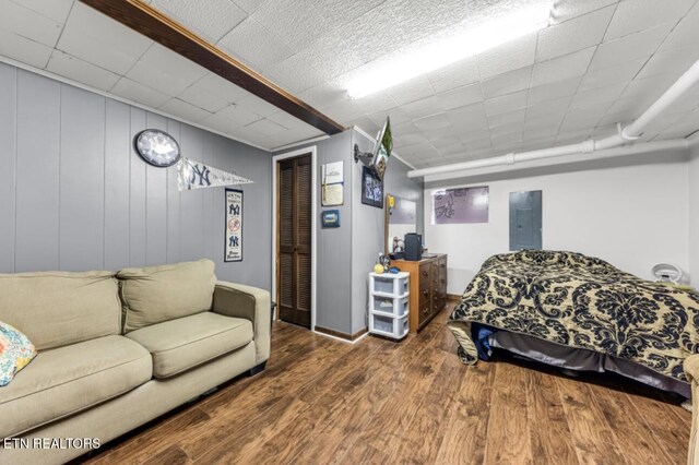 bedroom featuring electric panel, baseboards, a closet, and wood finished floors