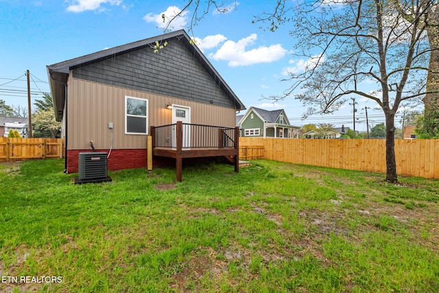 rear view of property featuring central AC unit, a fenced backyard, and a yard