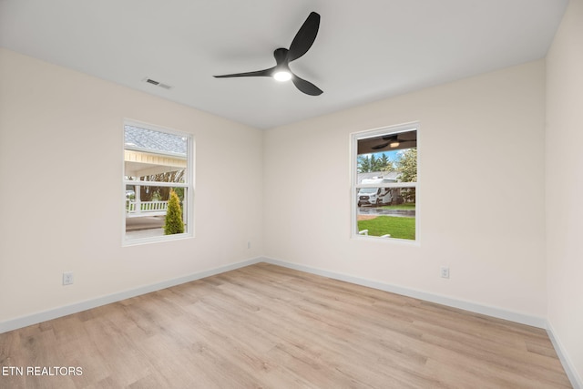 empty room with baseboards, visible vents, a healthy amount of sunlight, and wood finished floors