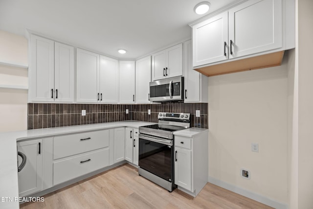 kitchen featuring backsplash, white cabinets, appliances with stainless steel finishes, and light wood-style floors