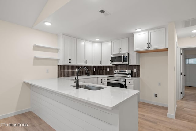 kitchen featuring visible vents, a sink, stainless steel appliances, and a peninsula