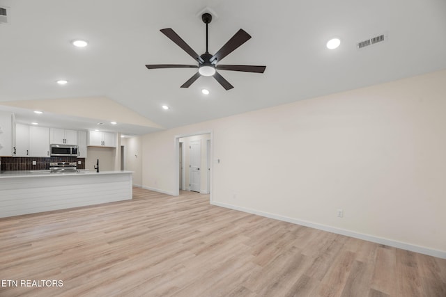 unfurnished living room featuring lofted ceiling, light wood-type flooring, baseboards, visible vents, and a ceiling fan