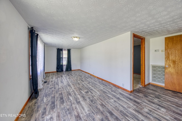 unfurnished room featuring a textured ceiling, baseboards, and wood finished floors