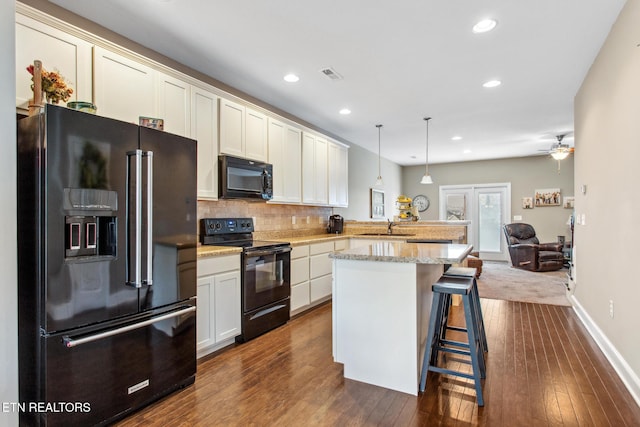 kitchen featuring a peninsula, dark wood-style floors, open floor plan, visible vents, and black appliances