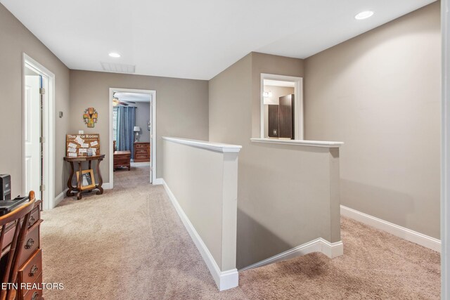 hallway featuring carpet floors, an upstairs landing, and baseboards