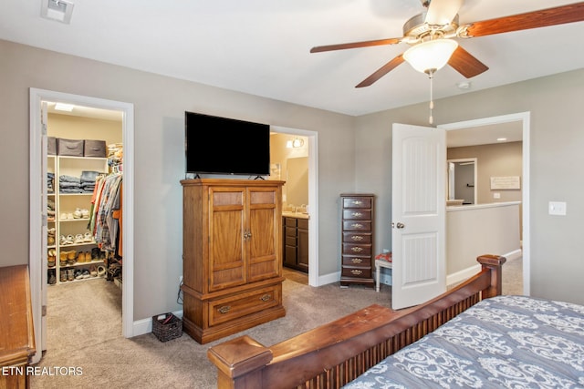 bedroom with a closet, visible vents, baseboards, a walk in closet, and light colored carpet