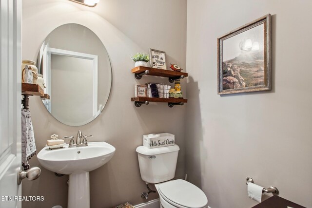 half bathroom featuring toilet and a sink