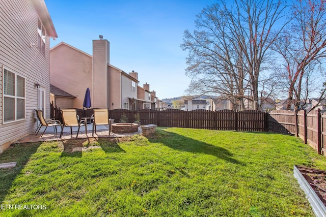 view of yard with a fenced backyard, a fire pit, and a patio
