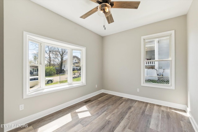 empty room featuring baseboards, visible vents, wood finished floors, and ceiling fan