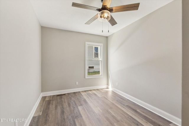 unfurnished room with wood finished floors, baseboards, ceiling fan, and visible vents