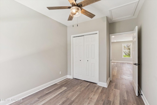 unfurnished bedroom featuring baseboards, a closet, attic access, and light wood finished floors