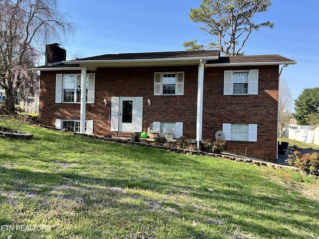 view of front of home featuring brick siding, a chimney, and a front yard