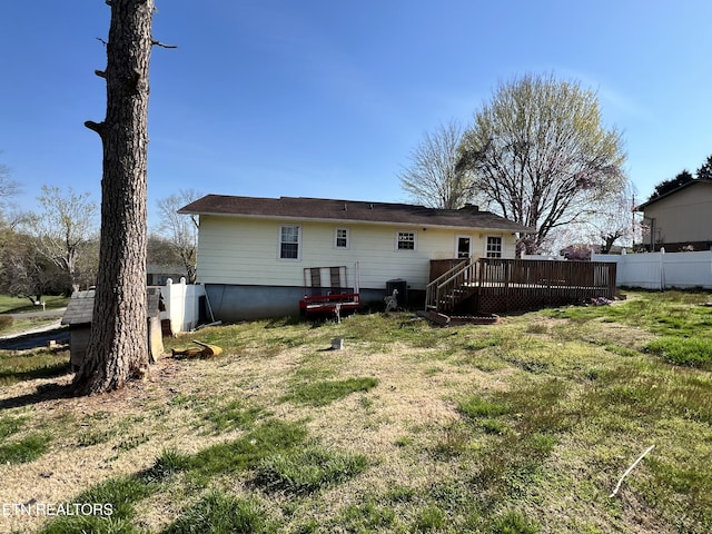 back of house featuring fence, a wooden deck, and a lawn