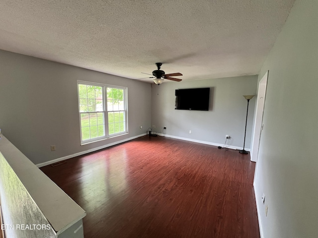 interior space with ceiling fan, baseboards, dark wood-style flooring, and a textured ceiling