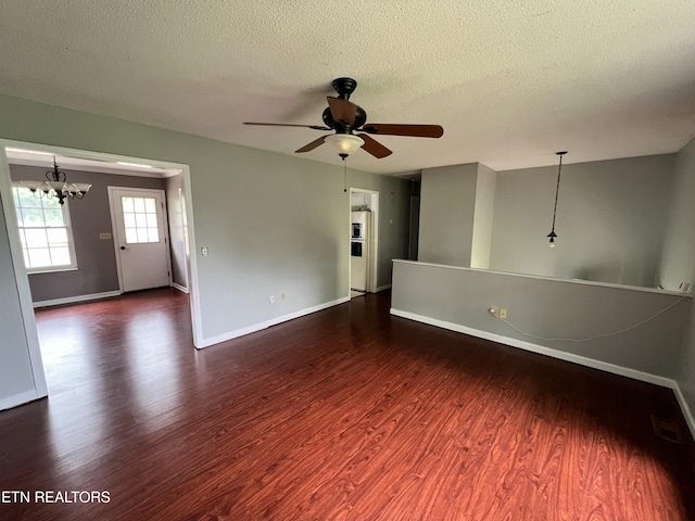 empty room featuring wood finished floors, a textured ceiling, ceiling fan with notable chandelier, baseboards, and visible vents