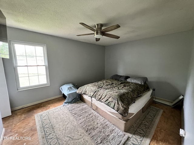 bedroom featuring a ceiling fan, baseboards, and a textured ceiling