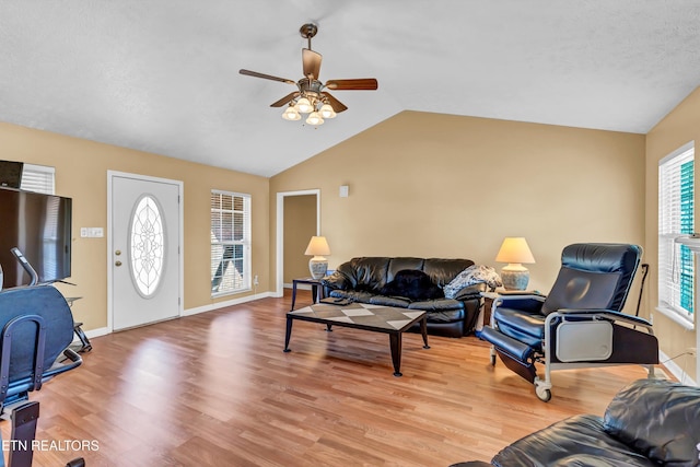 living area featuring light wood-style floors, baseboards, a ceiling fan, and vaulted ceiling