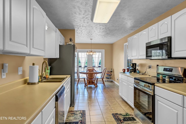 kitchen with an inviting chandelier, white cabinets, and stainless steel appliances