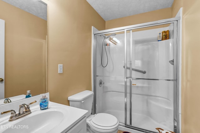 full bath featuring a shower stall, vanity, a textured ceiling, and toilet