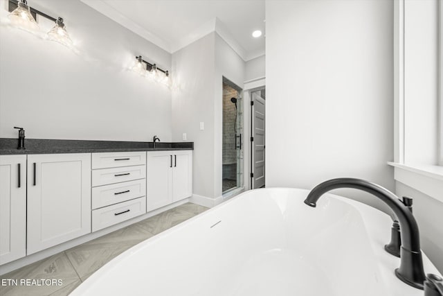 bathroom featuring crown molding, a sink, a freestanding bath, a stall shower, and baseboards