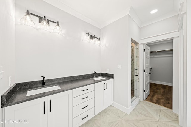 bathroom featuring a stall shower, a sink, ornamental molding, and a walk in closet