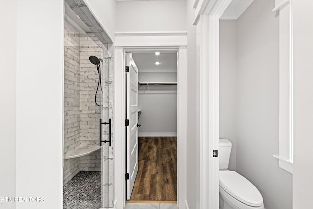 full bathroom featuring a shower stall, wood finished floors, a spacious closet, and toilet