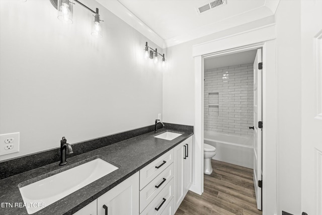 bathroom with toilet, wood finished floors, a sink, and visible vents