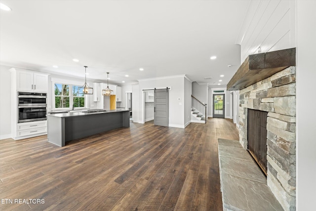 kitchen with a fireplace, double oven, white cabinetry, a barn door, and open floor plan