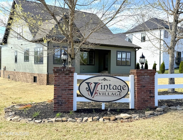 community / neighborhood sign with a yard and fence