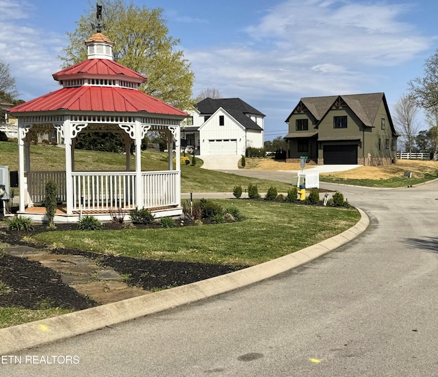view of property's community with an attached garage, a yard, driveway, and a gazebo