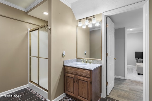 bathroom with vanity, a shower stall, crown molding, and baseboards