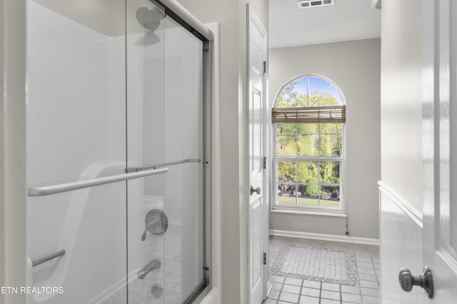 bathroom with tile patterned floors, visible vents, shower / bath combination with glass door, and baseboards