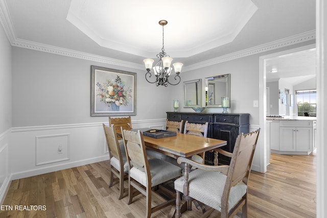 dining room featuring a raised ceiling, an inviting chandelier, and light wood finished floors