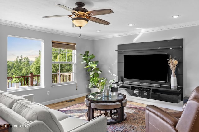 living area featuring visible vents, baseboards, ornamental molding, wood finished floors, and a ceiling fan