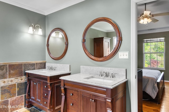 ensuite bathroom featuring crown molding, a ceiling fan, a sink, and two vanities
