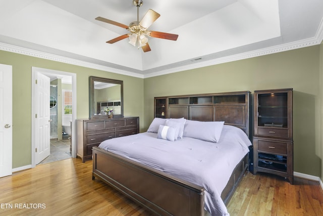 bedroom featuring ornamental molding, a raised ceiling, wood finished floors, and visible vents