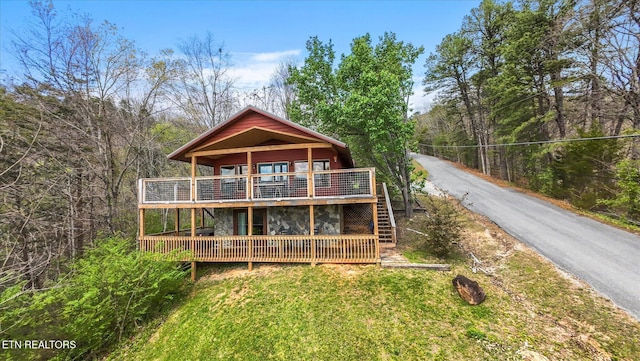 back of property with aphalt driveway, stairway, and a wooden deck