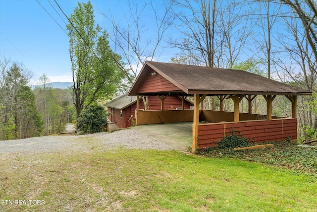 view of property exterior featuring gravel driveway, a carport, and a lawn