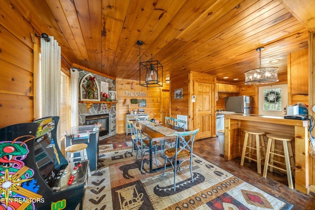 dining room with wood walls, a stone fireplace, and wood ceiling