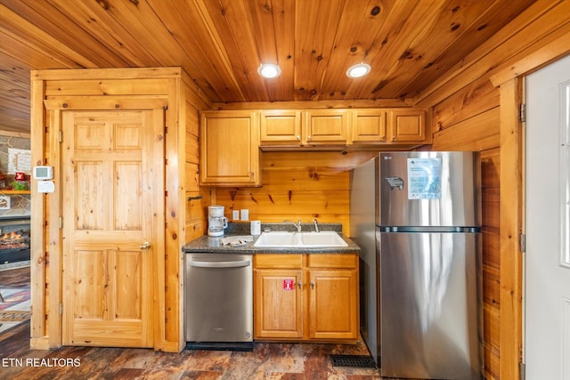 kitchen featuring wood ceiling, dark countertops, a sink, and stainless steel appliances