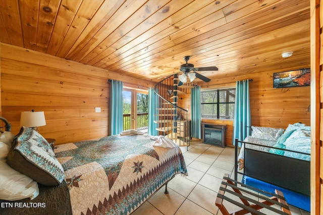 tiled bedroom with wooden walls, access to outside, and multiple windows